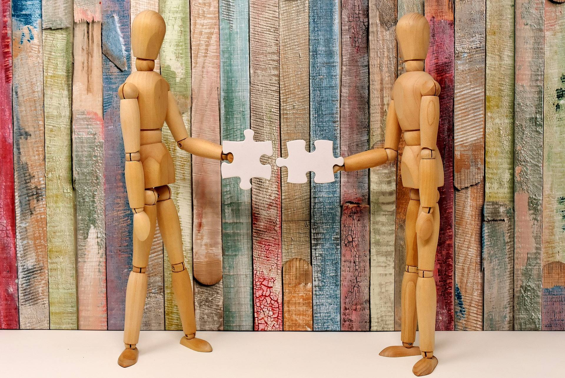 Deux mannequins en bois tenant les deux pièces complémentaires d'un puzzle